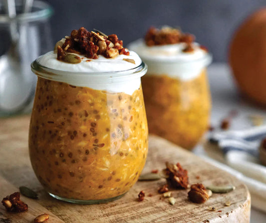 Pumpkin Pie Breakfast Oats in glass cups with nuts and cream.
