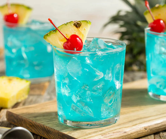 Bright Blue Raspberry Blast Party Punchs in glasses with cherries and pineapple slices. 