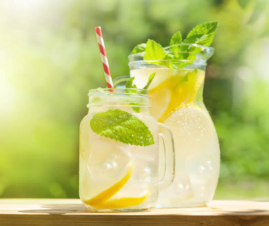 A pitcher and a mason jar of Lemon & Mint Cooler with lemon slices and sprigs of mint. 