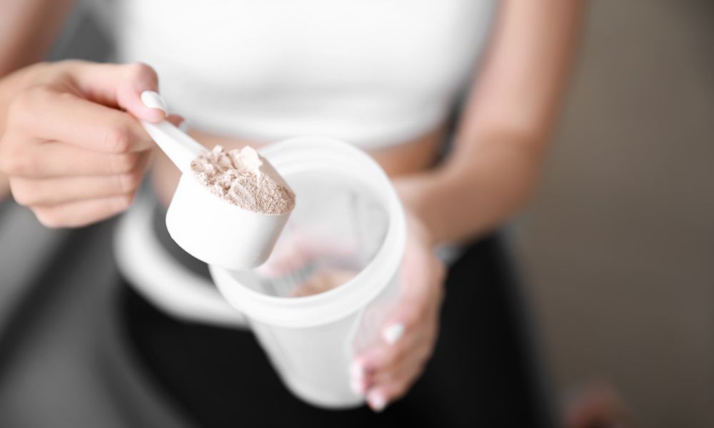 Athletic woman pours a scoop of whey protein into her BlenderBottle