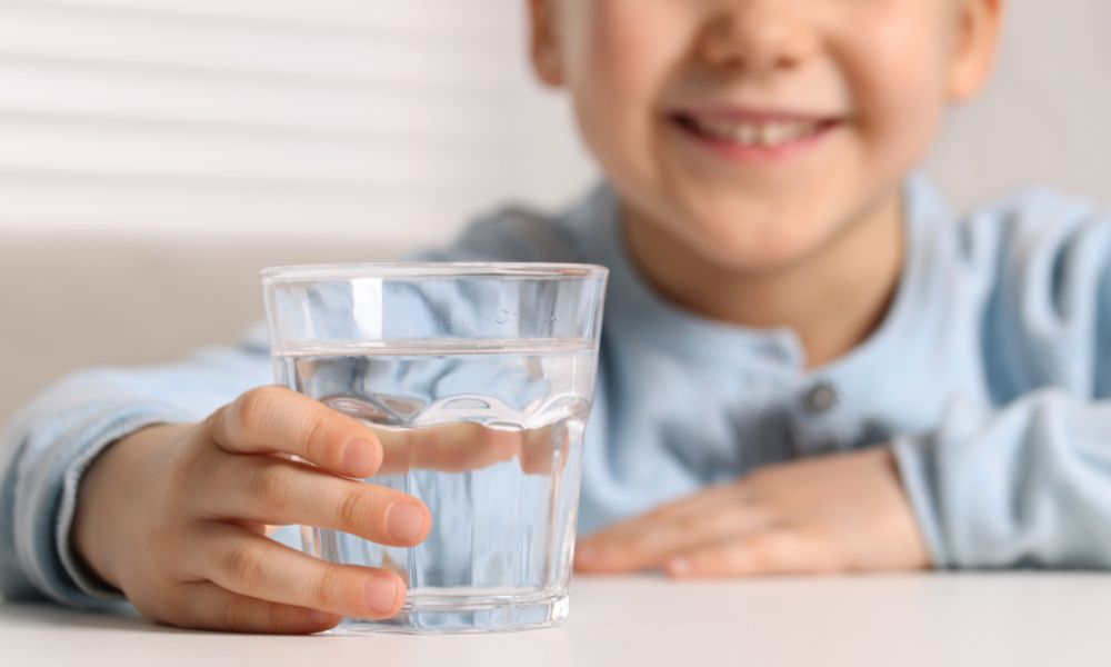 Little happy smiling boy with a glass of water. 