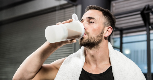 Athletic man drinking protein shake at the gym