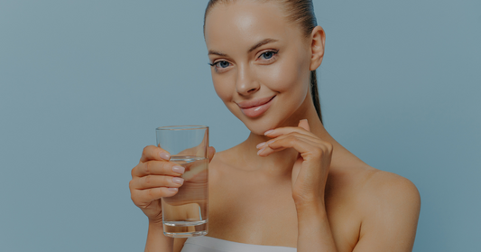 Smiling beautiful woman with gorgeous skin drinks a glass of water.