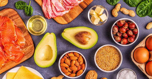 A table full of delicious Keto foods including avocados, nuts, meats, bacon, fish, eggs, cheese, etc. 