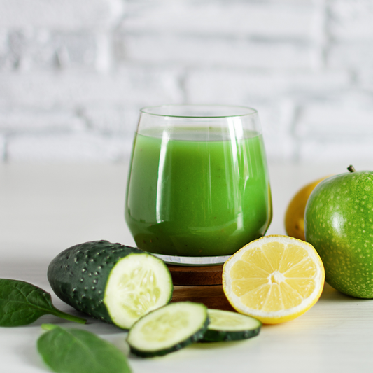 The Perfect Fall Green Smoothie in a glass with cucumbers, apples, lemons, and mint sprigs. 