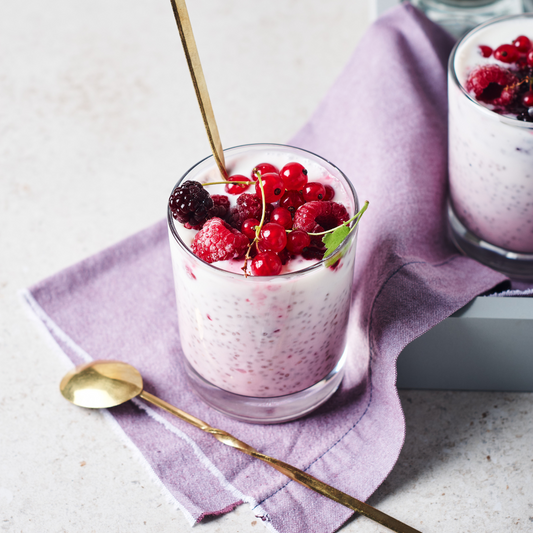 Two glasses of Raspberry Chia Seed Pudding with golden spoons and a lavender serviette. 